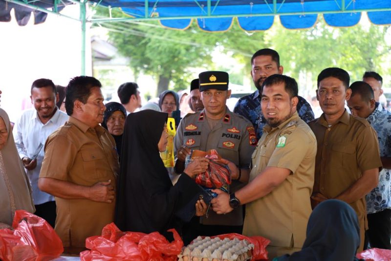 Pj Bupati Aceh Besar, Muhammad Iswanto SSTP MM didampingi Kadis Pangan Aceh Besar Ir Fuadi Ahmad dan Forkopimcam Darussalam menyerahkan sembako murah secara simbolis saat gelar Pasar Murah untuk masyarakat di Halaman Kantor Camat Darussalam, Lambaro Angan, Aceh Besar, Senin (19/06/2023).