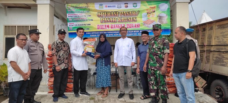 Plt Kepala Diskopukmdag Aceh Besar Trizna Darma ST, menyerahkan secara simbolis paket belanja operasi pasar khusus kepada salah seorang pembeli di Kecamatan Kuta Baro, Aceh Besar, Jum'at (17/11/2023).