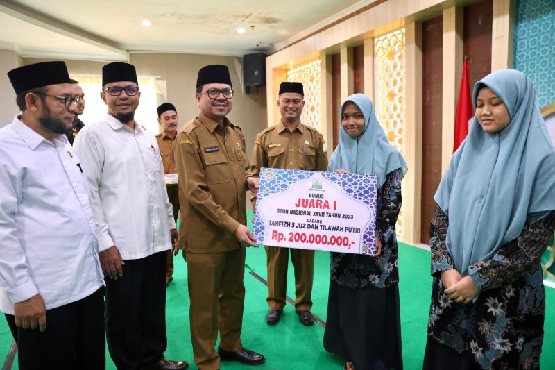Penjabat Sekretaris Daerah Aceh, Azwardi AP, M.Si., mewakili PJ Gubernur Aceh menyerahkan bonus juara STQH Nasional Ke-XXVII Tahun 2023, di Aula Kantor Dinas Syariat Islam Aceh Senin, (29/4/2024). 