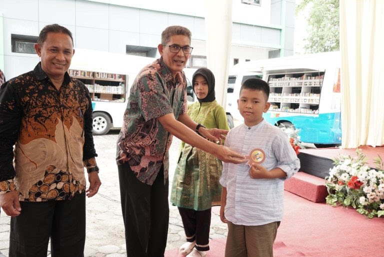 Asisten III Sekdakab Aceh Besar Jamaluddin S.Sos MM, menyematkan tanda peserta lomba bertutur kepada Siswa, di Kota Jantho, Kamis (27/06/2024) (Foto: noa.co.id/FA)