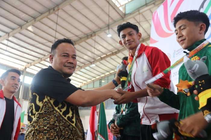 Pj. Sekda Aceh Timur T.Reza Rizki (Baju batik) didampingi Kadisporapar Syaril, mengalungkan medali emas, Jumat (12/7/2024). Foto: Aprizali Munandar/Noa.co.id