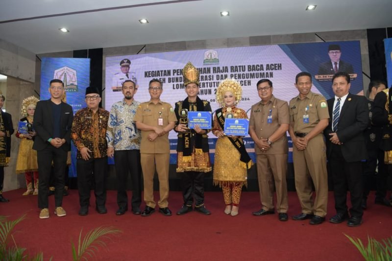 Asisten Administrasi Umum Sekda Aceh Iskandar, didampingi Kepala Dinas Arsip dan Perpustakaan Aceh Edi Yandra, menyerahkan hadiah sekaligus menobatkan Raja dan Ratu Baca Aceh terpilih, pada acara penobatan raja dan ratu baca Aceh, di Aula Perpustakaan Wilayah, Senin (5/8/2024). Foto: Humas Aceh