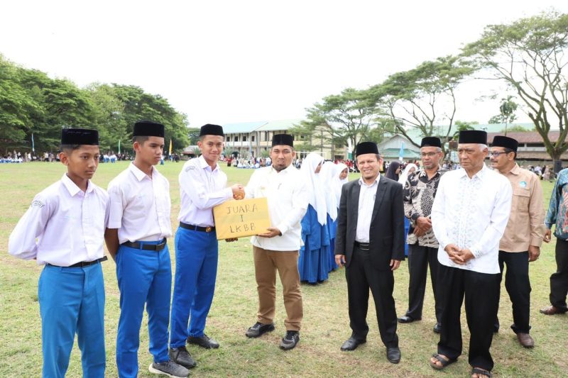 Pj Bupati Aceh Besar Muhammad Iswanto SSTP MM, menyerahkan hadiah kepada para santri berprestasi, pada Apel Tahunan 2024 dalam rangka Pekan Orientasi Kepesantrenan di lapangan Pesantren Modern Tgk Chiek Oemar Diyan, Indrapuri, Aceh Besar, Sabtu (24/8/2024). Foto: dok. MC Aceh Besar