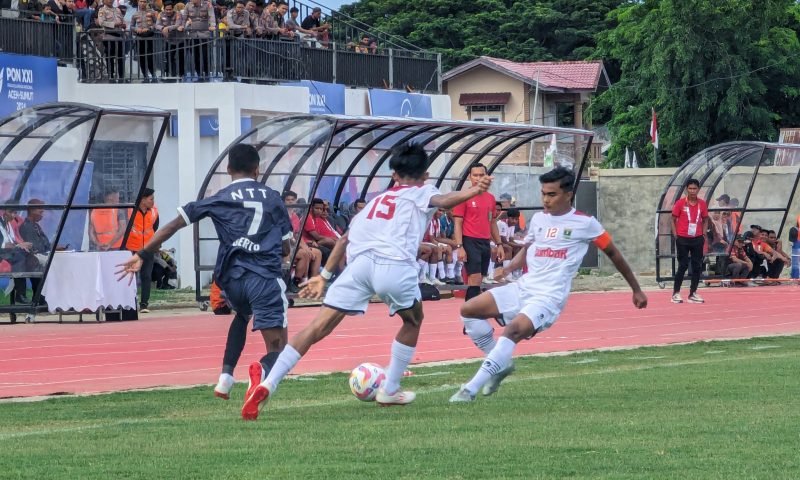 Dua pemain Sumbar memakai kustum warna putih coba menghadang pergerakan pemain NTT pada pertandingan lanjutan babak penyisihan Grup D, PON Aceh-Sumut ke XXI, di Stadion Blang Paseeh, Kota Sigli, Kabupaten Pidie, Provinsi Aceh, Jumat (6/9/2024) (Foto Amir Sagita.NOA.co.id).
