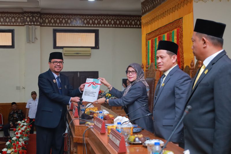 Pj Bupati Aceh Barat, Azwardi, saat menyerahkan dokumen Raqan APBK 2025 kepada Ketua DPRK Aceh Barat, Siti Ramazan. Foto: Humas DPRK Aceh Barat.