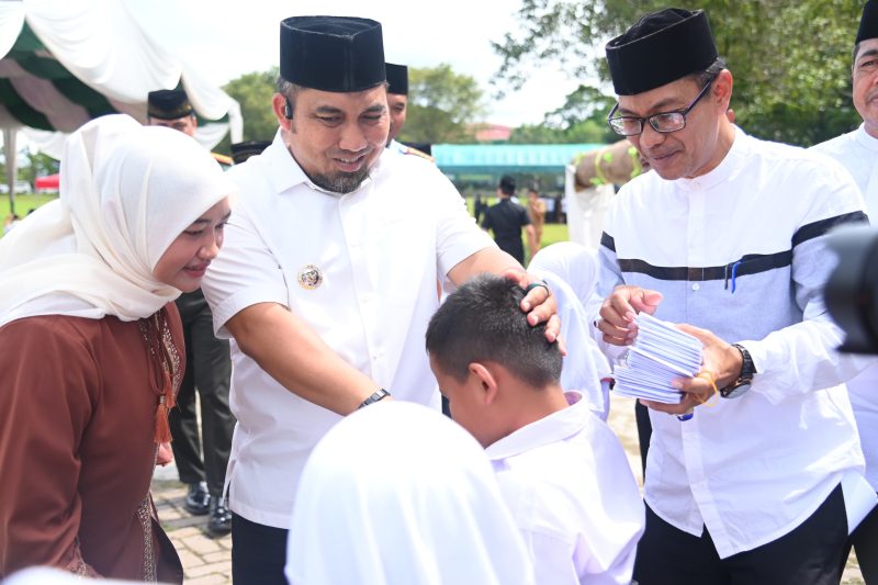 Pj Bupati Aceh Besar Muhammad Iswanto SSTP MM, didampingi Pj Ketua TP PKK Aceh Besar Cut Rezky Handayani SIP MM, dan Sahli Sekda Aceh Besar Adi Darma SPd MPd, menyerahkan santunan anak yatim pada Maulid Akbar, di Lapangan Bungoeng Jeumpa, Kota Jantho, Selasa (10/12/2024). Foto: Dok. MC Aceh Besar