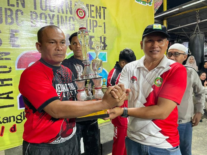 Ketua Pertina/Kadisparpora Aceh Besar Abdullah SSos, menyerahkan trofi juara umum pada turnamen DJBC Boxing Cup I Tahun 2024, kepada Pelatih DJBC Boxing Rucky, di Sasana Tinju DJBC, Gampong Bayu, Kecamatan Darul Imarah, Aceh Besar, Minggu (5/1/2025). Foto: Dok. MC Aceh Besar
