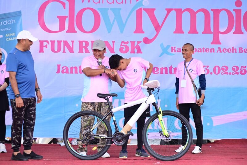 Plt Sekda Aceh Besar Bahrul Jamil menyerahkan hadiah doorprize kepada peserta Fun Run 5K di JSC, Kota Jantho, Minggu (24/02/2025). Foto: Dok. MC Aceh Besar