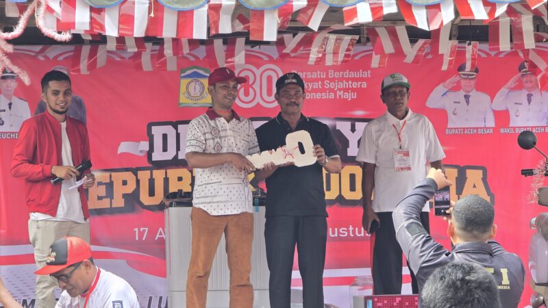 Wakil Bupati Aceh Besar, Drs. Syukri A. Jalil saat menyerahkan hadiah utama doorprize  secara simbolis kepada warga. Foto: Dok. Pribadi/NOA.co.id