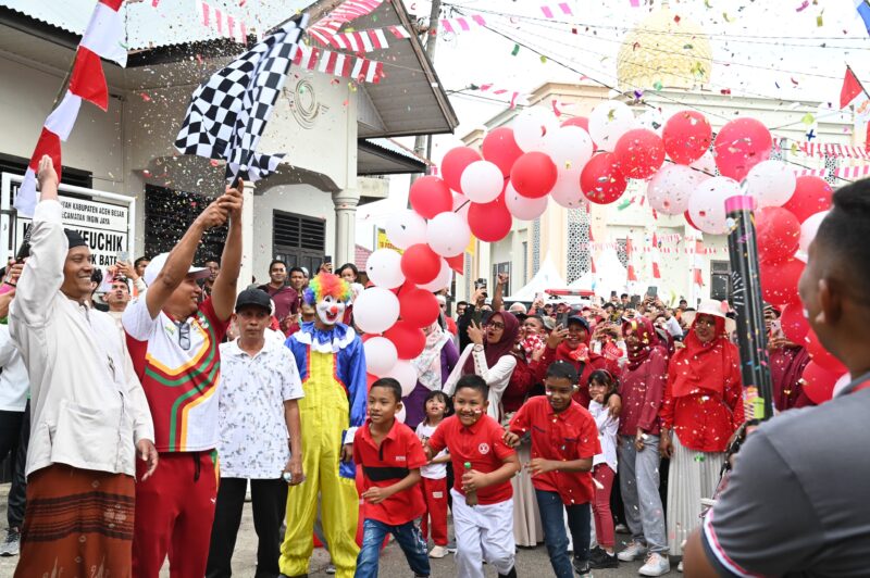 Kadisparpora Aceh Besar Abdullah SSos mengangkat bendera pada Pelepasan Gerak Jalan Santai di halaman Kantor Keuchik Gampong Lubok Batee, Kecamatan Ingin, Aceh Besar, Minggu (10/08/2025). Foto: Dok. MC Aceh Besar
