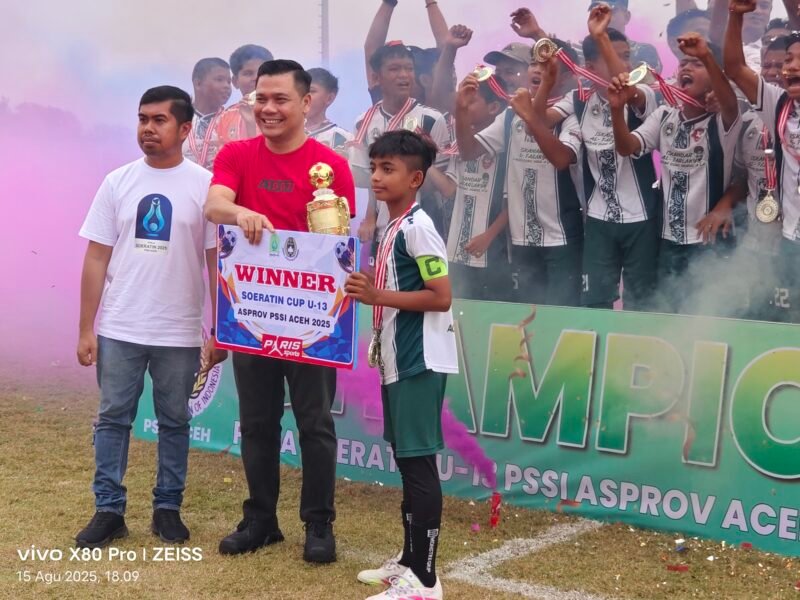 Wabup Pidie, Alzaizi Umar didampingin Sekum Asprov PSSI Aceh, Nazaruddin, saat menyerahkan piala kepada Afarlaky Aceh Timur sebagai juara pertama Piapa Soeratin Aceh U-13 di Stadion Blang Paseh, Kota Sigli, Jumat (15/8/2025) (Foto.Amir Sagita.NOA.co.id).