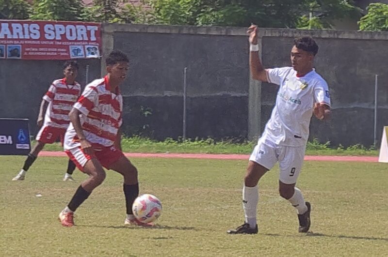Pemain Mutiara Raya memakai kustum putih merah menggiring bola dan dihadang pemain PSAB Aceh Besar pada Piala Soeratin U-17 di Stadion Blang Paseh, Kota Sigli, Kamis (21/8/2025) (Foto.Amir Sagita.NOA co.id)