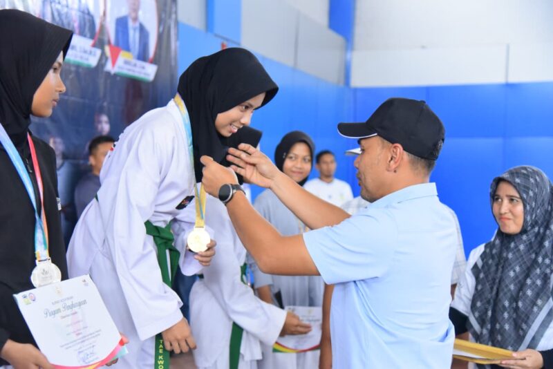 Ketua DPRK Aceh Besar Abdul Muchti mengalungi Medali kepada Juara Taekwondo PORKAB 2025 di JSC, Kota Jantho, Selasa (9/9/2025). Foto: Dok. MC Aceh Besar