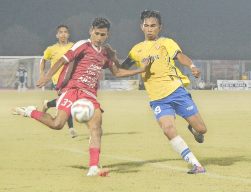 Pemain Mutiara Raya memakai kustum warna merah menggiring bola dan dibayang bayangi pemain Adam Depok Nagan Raya pada pertandingan lanjutan Piala Bupati Pidie, di Stadion Blang Paseh, Kota Sigli, Jumat malam (3/10/2025) (Foto.Amir Sagita.NOA.co.id).