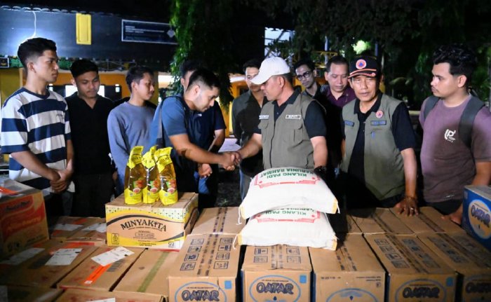 Bupati Aceh Besar, H. Muharram Idris (Syech Muharram), menyerahkan bantuan logistik kepada mahasiswa terdampak banjir dan longsor di Anjungan Aceh Tengah, Taman Ratu Safiatuddin, Banda Aceh, Kamis malam (4/12/2025). Foto: Dok. MC Aceh Besar