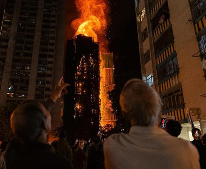 Orang-orang menyaksikan kebakaran hebat yang melalap sebuah gedung di Wang Fuk Court, sebuah kawasan hunian di Distrik Tai Po, New Territories, Hong Kong, Rabu (26/11/2025). (Dok. AP/Chan Long Hei)