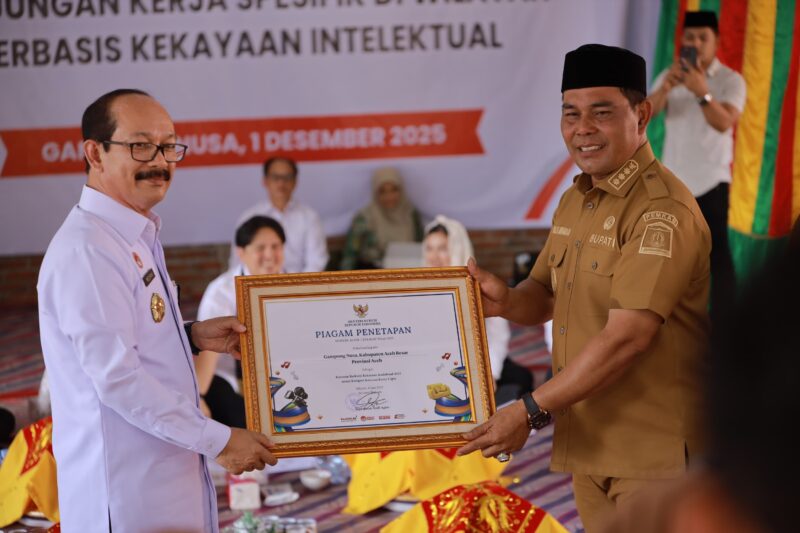 Bupati Aceh Besar, H Muharram Idris (Syech Muharram) menerima piagam penetapan Gampong Nusa sebagai kawasan berbasis kekayaan intelektual 2025, pada kunjungan kerja spesifik Komisi XIII DPR RI, di Gampong Nusa, Kecamatan Lhoknga, Kabupaten Aceh Besar, Senin (1/12/2025). Foto: Dok. Prokopim Pemkab Aceh Besar 