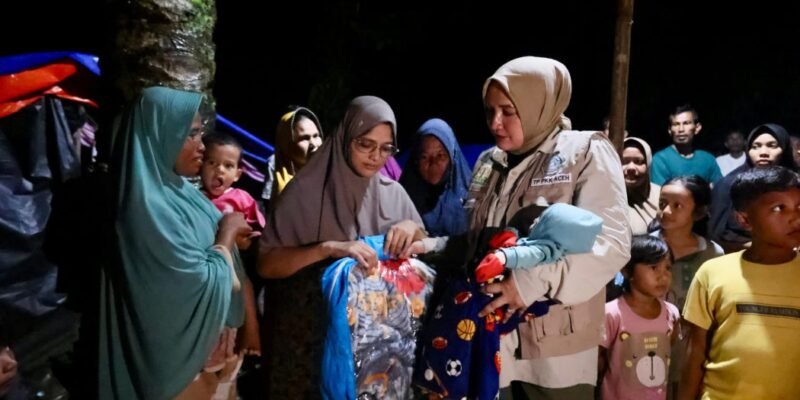 Ketua TP PKK Aceh, Marlina Muzakir, menyerahkan bantuan tanggap darurat kepada warga terdampak banjir bandang di Kecamatan Langkahan, Aceh Utara, Selasa (16/12/2025) malam. Foto: Dok. Biro Adpim Setda Aceh 