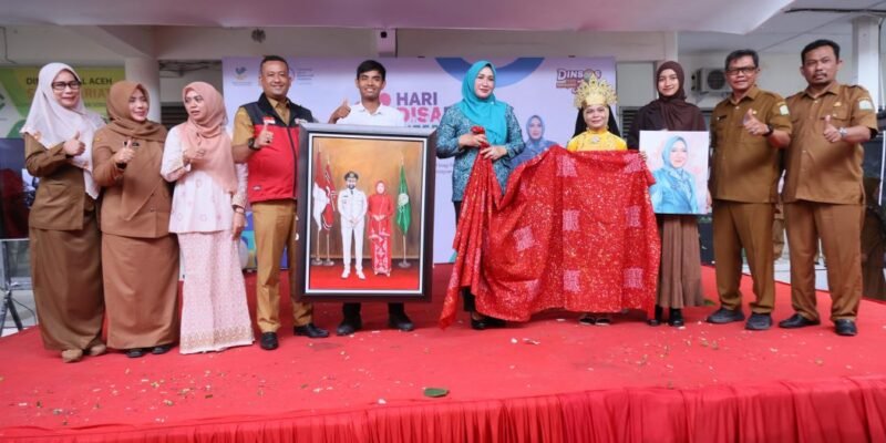 Ketua TP PKK Aceh Marlina Muzakir menerima batik tulis karya anak disabilitas rungu pada peringatan Hari Disabilitas Internasional 2025 di Dinas Sosial Aceh, Selasa (30/12/2025). Foto: Dok. Biro Adpim Setda Aceh