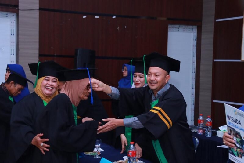 Bupati Aceh Jaya Safwandi menyematkan tali toga kepada salah satu wisudawan lanjut usia (lansia) pada Wisuda 177 peserta Sekolah Lansia Kabupaten Aceh Jaya yang digelar di Aula DPMPKB Aceh Jaya, Kamis (22/1/2026). Foto: Dok Mc Aceh Jaya.