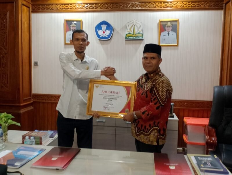 Ketua Komisi Informasi Aceh Junaidi menyerahkan sertifikat dan plakat penghargaan kualifikasi Informatif kepada Plt Kepala Dinas Pendidikan Aceh Murthalamuddin. Foto: Dok. Istimewa
