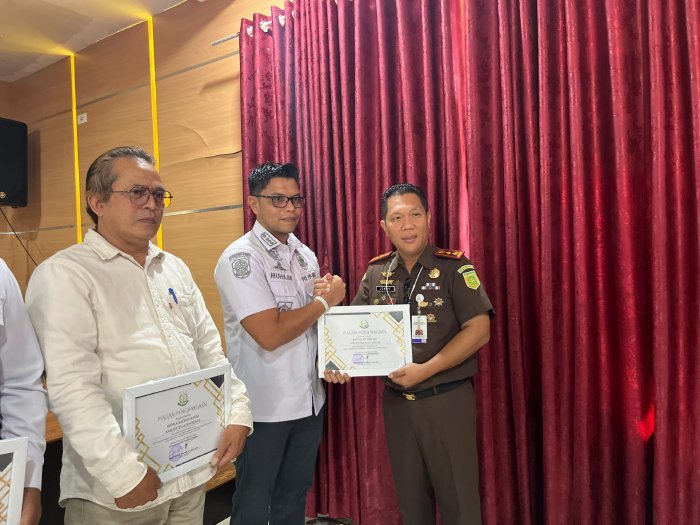 Kajari Aceh Besar Jemmy Novian Tirayudi, SH MH MSi menyerahkan piagam penghargaan kepada Kasatpol PP dan WH Aceh Besar Muhajir SSTP MAP, di Aula Baharuddin Lopa Kejari Aceh Besar, Kota Jantho, Rabu (25/2/2026). Foto: Dok. MC Aceh Besar