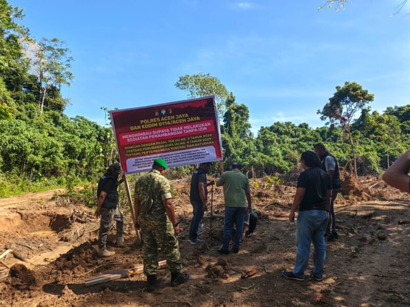 Personel gabungan TNI dan Polri memasang spanduk himbauan larangan aktivitas penambangan tanpa izin di kawasan tambang Desa Panggong, Kecamatan Krueng Sabee, Kabupaten Aceh Jaya, Jumat (6/2/2026). Foto: Dok. Polres Aceh Jaya