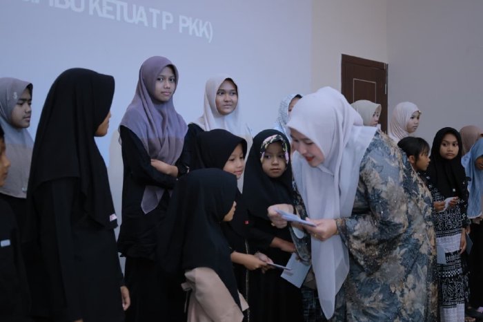 Ketua TP PKK Aceh Besar Hj. Rita Mayasari menyerahkan santunan kepada anak yatim dalam kegiatan buka puasa bersama di Orion Hall, Darul Imarah, Aceh Besar, Sabtu (7/3/2026). Foto: Dok. MC Aceh Besar