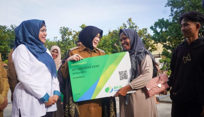 Walikota Banda Aceh Illiza Saaduddin menyerahkan kartu jaminan sosial kepada tenaga kerja rentan secara simbolis di Halaman Balai Kota Banda Aceh, Jumat (15/5/2026). Foto: Dok. Humas Pemko Banda Aceh
