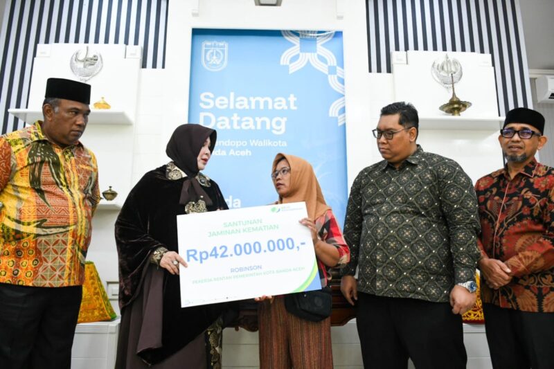 Wali Kota Banda Aceh, Illiza Sa’aduddin Djamal, didampingi Kepala BPJS Ketenagakerjaan Banda Aceh, Aziz Muslim, menyerahkan secara simbolis kartu kepesertaan BPJS Ketenagakerjaan dan santunan kematian kepada ahli waris peserta di Pendopo Wali Kota Banda Aceh, Kamis (4/6/2026). Foto: Dok. Prokopim Kota Banda Aceh