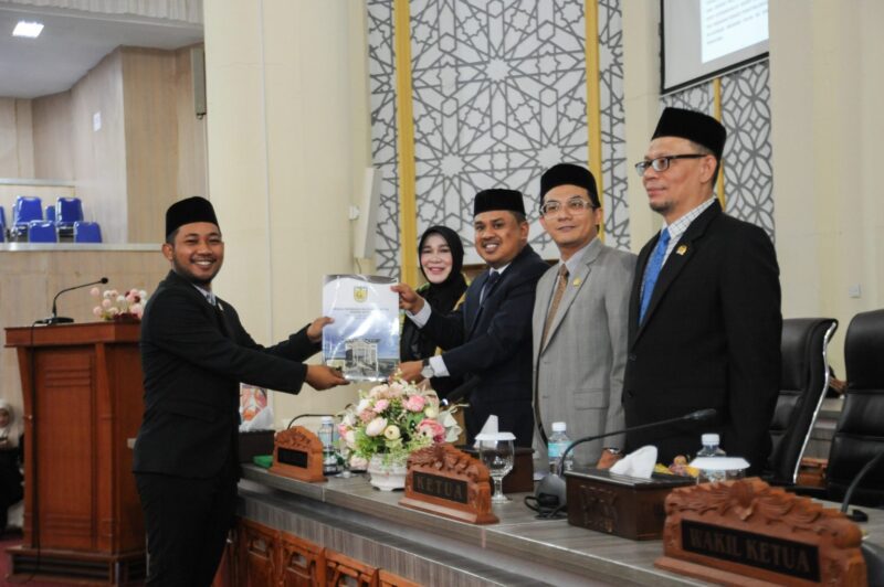 M. Zidan Al Hafidh, S.Ked., M.M., anggota Banggar saat menyerahkan pandangan banggar kepada pimpinan, Wakil Ketua I DPRK Banda Aceh, Daniel Abdul Wahab, didampingi Ketua DPRK Banda Aceh, Irwansyah, ST, serta Wakil Ketua II, Musriadi Aswad. Serta disaksikan oleh Wali Kota Banda Aceh, Illiza Sa'aduddin Djamal dalam rapat paripurna DPRK Banda Aceh dengan agenda penyampaian pendapat, usul, dan saran Banggar terhadap Rancangan Qanun (Raqan) tentang Laporan Keterangan Pertanggungjawaban (LKPJ) Wali Kota Banda Aceh, di Gedung DPRK Banda Aceh, Kamis (23/7/2026). Foto: Dok. DPRK Banda Aceh