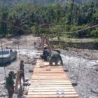 Personel Babinsa Posramil Lawe Sumur bersama teknisi lapangan dan masyarakat bergotong royong memasang papan lantai Jembatan Gantung Perintis di Desa Teger Miko, Kecamatan Lawe Sumur, Aceh Tenggara, Senin (6/7/2026). Foto: Dok. Istimewa