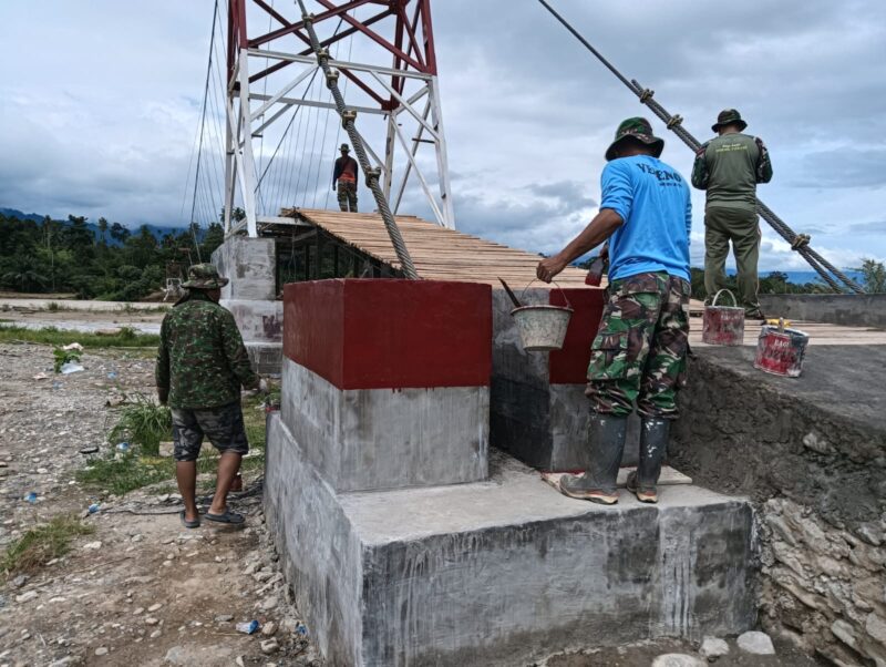 Babinsa Kodim 0108/Aceh Tenggara bersama masyarakat, teknisi, dan personel terkait bergotong royong memasang papan lantai Jembatan Gantung Perintis di Desa Kuta Ujung, Kecamatan Darul Hasanah, Kabupaten Aceh Tenggara, Selasa (4/8/2026). Foto: Dok. Istimewa 