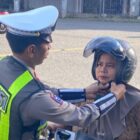 Personil Satlantas Polres Abdya memakai helm kepada salah seorang pengguna jalan raya. Foto. Dok. Teukunizar/noa.co.id