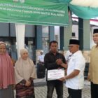 Anggota Baitul Mal Aceh Fahmi M Nasir menyerahkan bantuan modal usaha kepada penerima manfaat dalam program penyaluran dana infak tahap kedua di halaman Kantor BMA, Banda Aceh, Rabu (19/8/2026). Foto: Dok. Istimewa