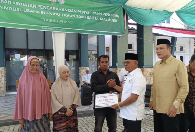 Anggota Baitul Mal Aceh Fahmi M Nasir menyerahkan bantuan modal usaha kepada penerima manfaat dalam program penyaluran dana infak tahap kedua di halaman Kantor BMA, Banda Aceh, Rabu (19/8/2026). Foto: Dok. Istimewa 