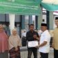 Anggota Baitul Mal Aceh Fahmi M Nasir menyerahkan bantuan modal usaha kepada penerima manfaat dalam program penyaluran dana infak tahap kedua di halaman Kantor BMA, Banda Aceh, Rabu (19/8/2026). Foto: Dok. Istimewa 