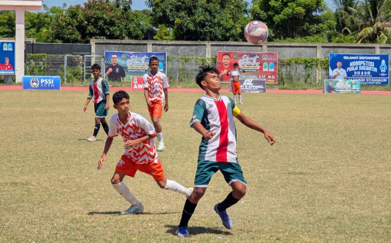 Pemain MAN I Pidie memakai kustum hijauh putih saat menggiring bola dan dibayang-bayangi pemain Persidi IDI pada laga delapan besar Piala Soeratin U-15 Regional Aceh di Stadion Blang Paseh Kota Sigli, Kamis (27/8/2026) (Foto.Amir Sagita).
