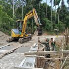 Personel Satgas TMMD Reguler ke-129 Kodim 0102/Pidie memasang cerucuk kayu menggunakan mini excavator sebagai penahan bantaran jalan pada pembangunan Jembatan Box Culvert di Desa Lhok Panah, Kecamatan Sakti, Jumat (7/8/2026). Foto: Dok. Istimewa 