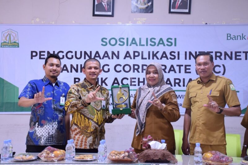 Perwakilan Bank Aceh Syariah menyerahkan plakat kepada perwakilan Cabang Dinas Pendidikan Wilayah Bireuen dalam kegiatan sosialisasi penggunaan Internet Banking Corporate (IBC) di SMAN 1 Bireuen, Selasa (22/9/2026). Foto: Dok. Istimewa 