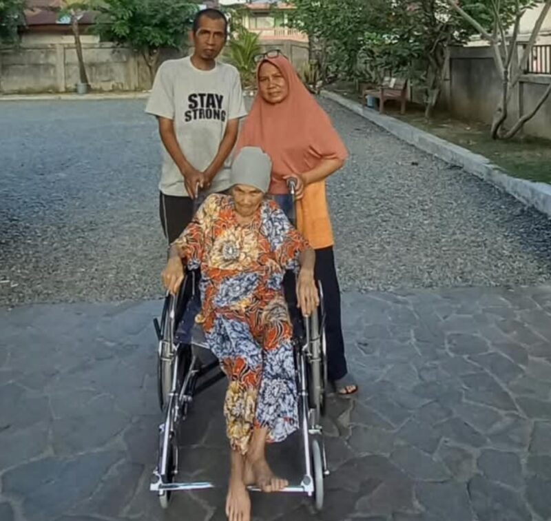 Sariana Hasibuan, lansia 76 tahun, menggunakan kursi roda bantuan Pemerintah Aceh melalui Dinas Sosial Aceh, didampingi anggota keluarga di Banda Aceh, Kamis (24/9/2026). Foto: Dok. Dinsos Aceh