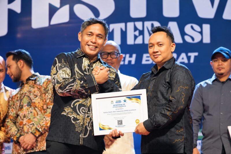 Sekda Aceh Barat, Dr. Ir. Kurdi, ST, MT, MH, IPM, ASEAN-Eng, menyerahkan penghargaan kepada Sekjen SMSI Aceh Barat, Riosa, sebagai Organisasi Media Pegiat Literasi Kabupaten Aceh Barat Tahun 2026, pada malam penutupan Festival Literasi Aceh Barat 2026, Sabtu (26/9/2026). Foto: Dok. SMSI Aceh Barat