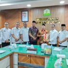 Bupati Aceh Jaya, Safwandi berbaju batik kuning merah, menyerahkan berkas kepada Plt Sekda Aceh, Taufik, dalam rapat persiapan PORA XV/2026, di ruang rapat Sekretaris Daerah Aceh, Rabu (7/10/2026). Foto: Dok. Pemkab Aceh Jaya
