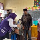 Ketua Posyandu Kabupaten Aceh Barat, Afrinda Novalia, menyerahkan bantuan perlengkapan sekolah kepada siswa terdampak bencana hidrometeorologi di SDN Alue Lhok, Kecamatan Pante Ceureumen, Kamis (29/10/2026). Foto: Dok. Istimewa