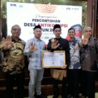 Bupati Aceh Jaya, Safwandi, (baju putih bermotif kotak-kotak dan peci hitam), bersama jajaran pejabat dan perwakilan Gampong Kabong saat menerima penghargaan Desa Percontohan Antikorupsi dari KPK RI di Banda Aceh, Rabu (21/10/2026). Foto: Dok. DPMPKB Aceh Jaya
