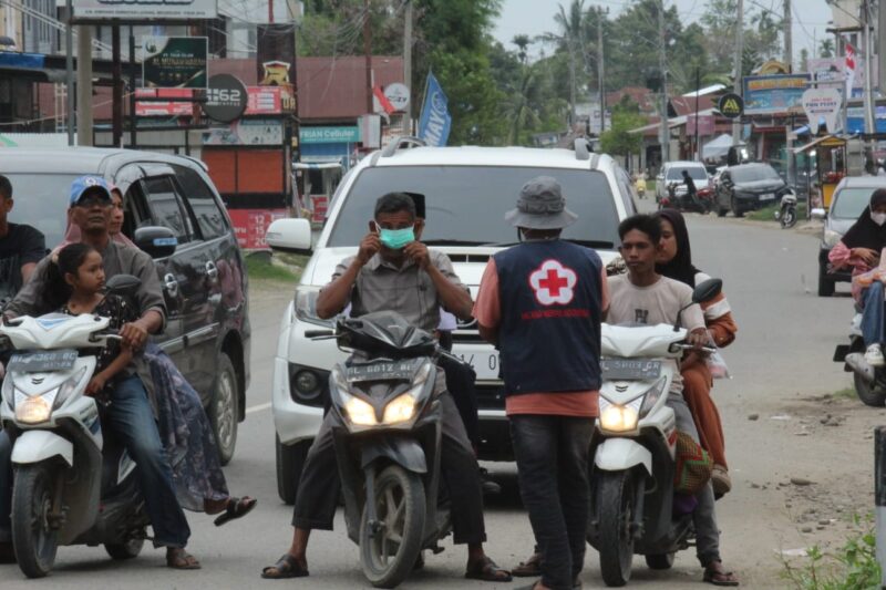 Relawan PMI Pidie Jaya membagikan masker kepada warga pelintas, Simpang Jalan Layang. Meureudu (19/10/2026). Foto:Dok/Nasruddin 