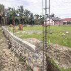Kondisi pagar SMP Negeri 4 Muara Tiga, tidak dikerjakan lagi dan tanpa papan informasi proyek, (Foto.Amir Sagita.NOA.co.id).